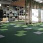 Open space biurowca, na podłodze charakterystyczne płytki dywanowe w zielonych barwach