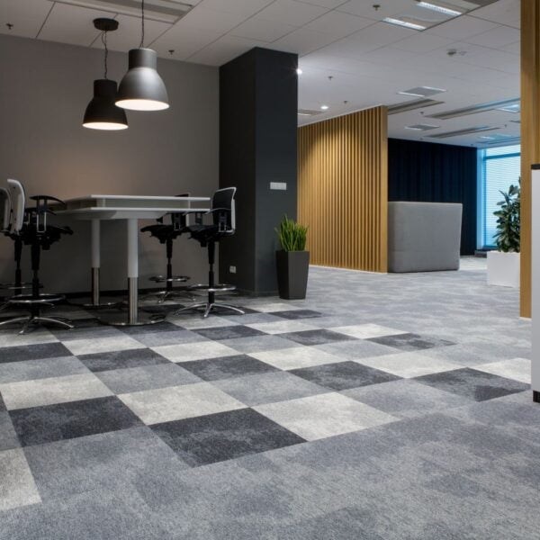 Wnętrze biura z drewnianymi lamelami na drugim planie i wykładziną w szachownicę w różnych odcieniach szarości