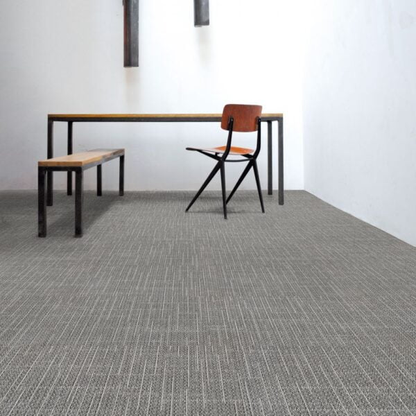 Pomieszczenie z biurkiem drewnianym i krzesłem, podłoga okryta jest wykładziną biurową