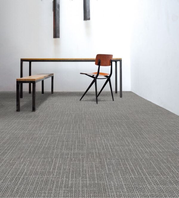 Pomieszczenie z biurkiem drewnianym i krzesłem, podłoga okryta jest wykładziną biurową